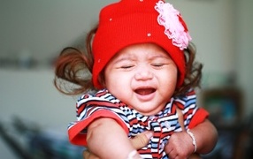 Девочка в красной шапке плачет на руках