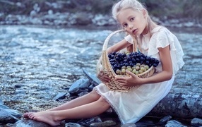Девочка с корзиной винограда сидит у воды