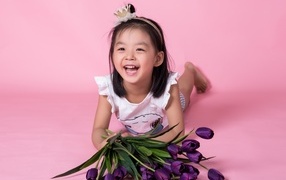 Девочка азиатка в букетом тюльпанов на розовом фоне