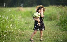 Девочка азиатка в шляпе с букетом цветов