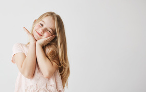 Красивая маленькая длинноволосая девочка на сером фоне