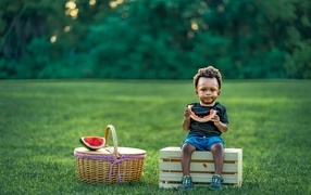 Темнокожий мальчик ест арбуз на природе