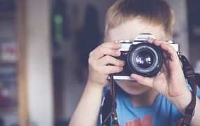 Мальчик держит в руках старый фотоаппарат