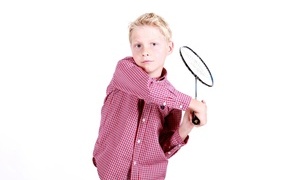 Мальчик в рубашке с ракеткой в руках на белом фоне