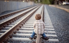 Мальчик сидит на железнодорожных рельсах