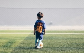 Мальчик футболист с мячом на поле