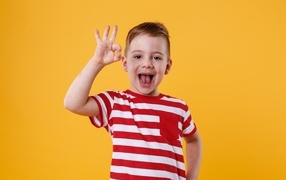 Веселый мальчик в полосатой футболке на оранжевом фоне