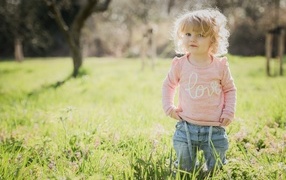 Кудрявая девочка в зеленой траве