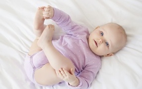 Милый голубоглазый малыш на белом покрывале