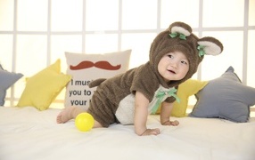 Смешной ребенок азиат в костюме на кровати