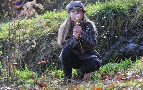 Девочка в кепке дует на одуванчик