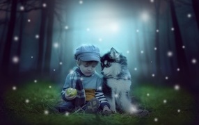 Маленький мальчик с щенком сидят на траве в лесу