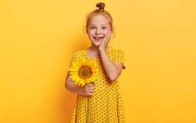 Маленькая рыжеволосая девочка с подсолнухом в руках