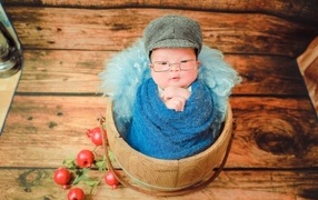 Новорожденный малыш в покрывале с кепкой на голове