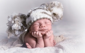 Новорожденный младенец в большой вязаной шапке