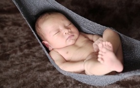 Новорожденный спящий малыш в вязаном гамаке