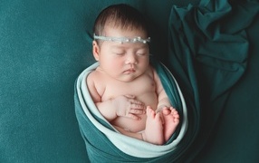 Фотография спящей новорожденной девочки на зеленом фоне
