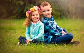 Рыжеволосые мальчик и девочка сидят на траве