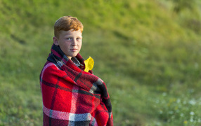 Рыжеволосый мальчик укутан пледом осенью 