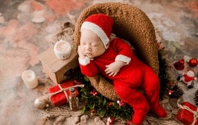 Спящий новорожденный ребенок в красном новогоднем костюме