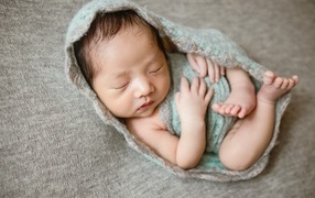 Крошечный новорожденный малыш на сером фоне