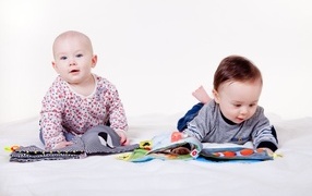 Два маленьких ребенка на кровати с мягкими книгами