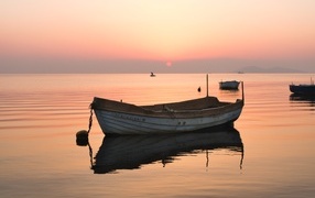Старая лодка стоит на воде на закате солнца