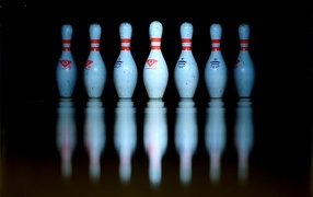 Кегли для боулинга отражаются в черной поверхности 