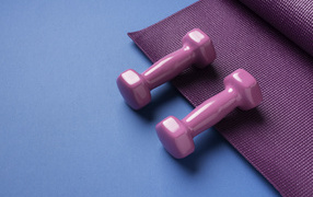 Розовые гантели и коврик на голубом фоне