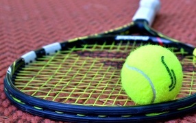 Two rackets and a yellow tennis ball