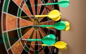 Желтые и зеленые дротики в мишени 