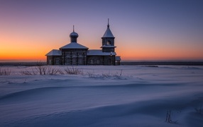 Старая деревянная церковь в снежной пустыне на закате