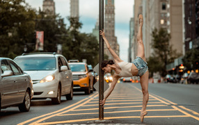 Девушка делает шпагат у столба в городе