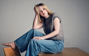 Актриса Дакота Фэннинг в джинсах сидит на столе