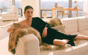 Актриса Люси Хейл в черном платье лежит на диване