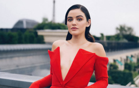 Актриса Люси Хейл в красном наряде стоит на мосту