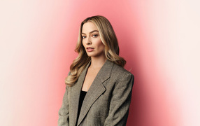 Актриса Марго Робби в сером пиджаке на розовом фоне