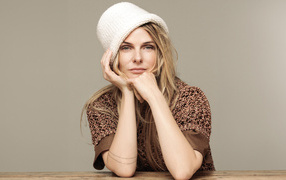 Актриса Ребекка Фергюсон в белой шляпе сидит за столом