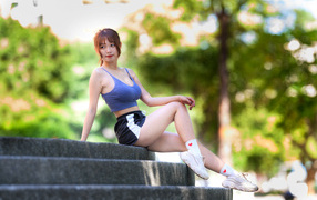 Athletic Asian woman in sneakers sitting on the steps