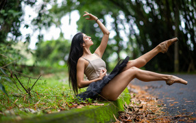 Девушка балерина в короткой юбке сидит на земле