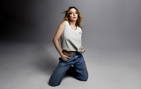Британская актриса Джоди Комер в джинсах на сером фоне