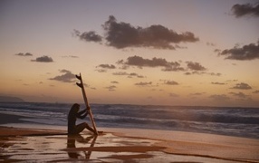 Девушка серфингистка сидит на берегу моря