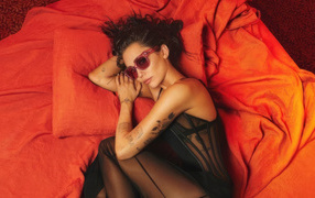 Милая Майли Сайрус лежит на красном покрывале