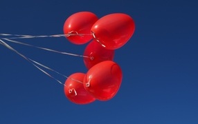Красные воздушные шары на нитке на фоне голубого неба