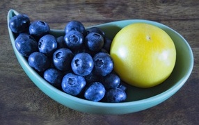 Ягоды черники на тарелке с зеленой сливой