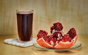 Красный гранат на столе со стаканом сока