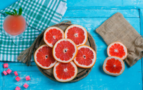 Нарезанный грейпфрут с соком на голубом столе