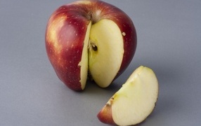 Разрезанное красное яблоко на сером фоне