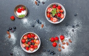 Тарелки с мюсли и ягодами на сером столе с пудрой