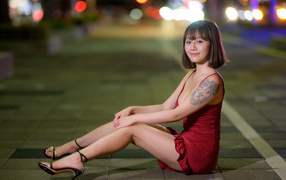 Азиатка с татуировкой на руке в красном платье